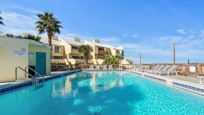 Une piscine avec des chaises longues et un bâtiment doté de nombreux balcons.