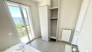 A modern bedroom with a bed, a wardrobe, a radiator, and a balcony with a view. - Villa Ipnotica - Panoramic Views Plus Exquisite Pool - Sleeps 7 - Very Stylish (Spoleto)