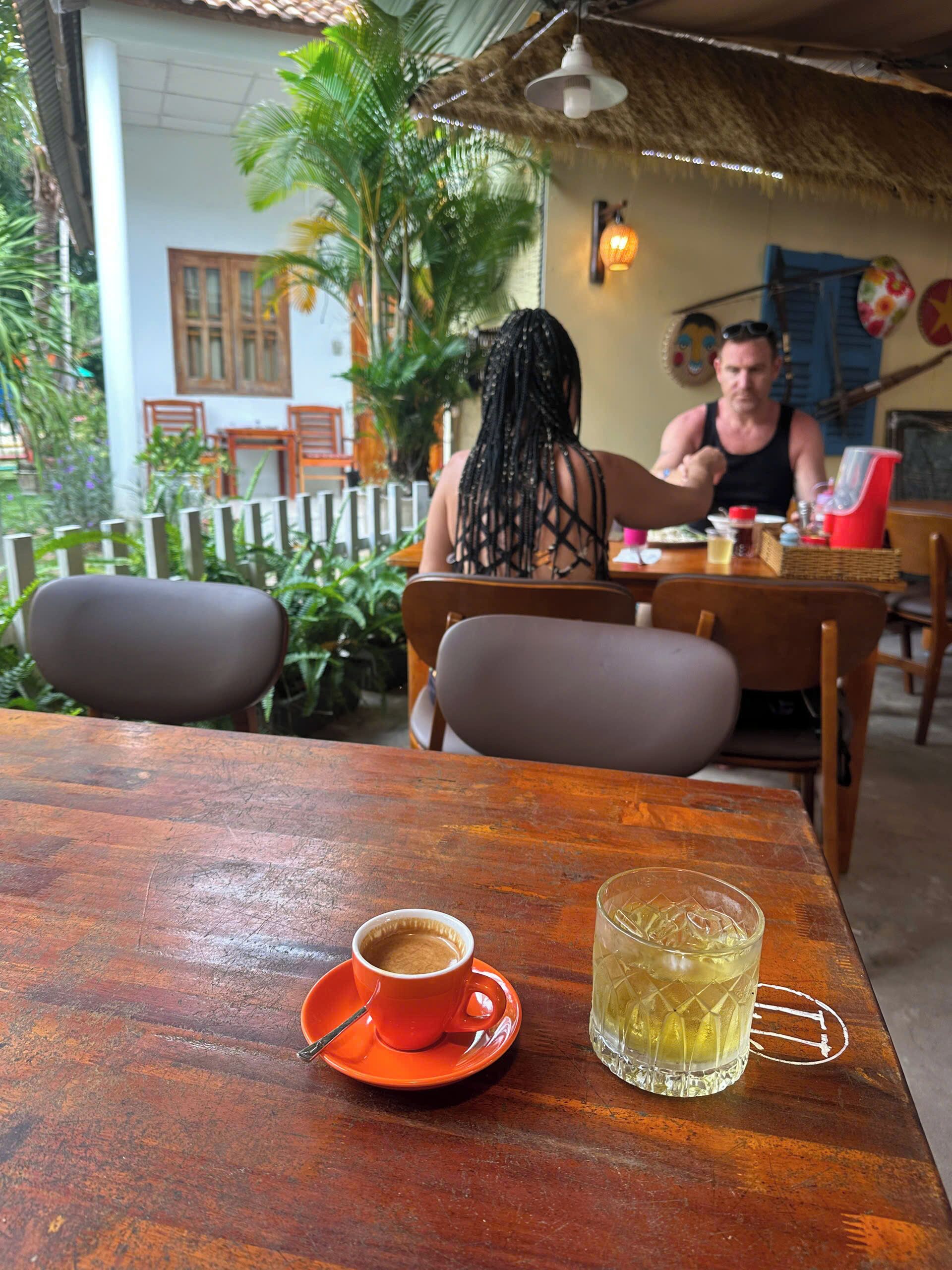 A wooden table with a cup of coffee and a glass of iced tea.