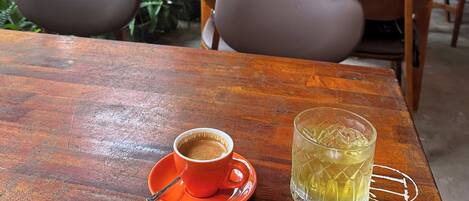 A wooden table with a cup of coffee and a glass of iced tea.