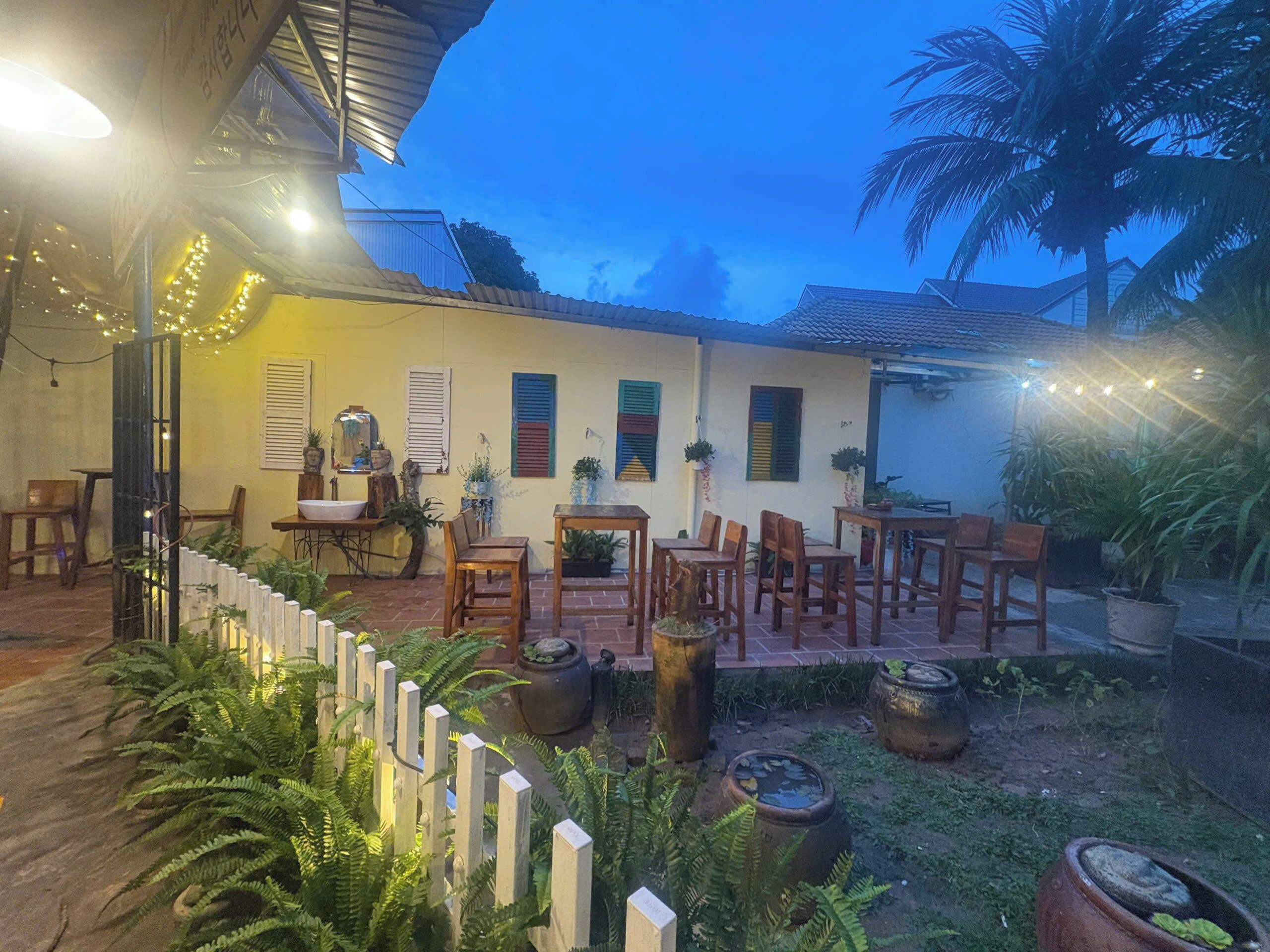 An outdoor patio area with wooden furniture, potted plants, and string lights.