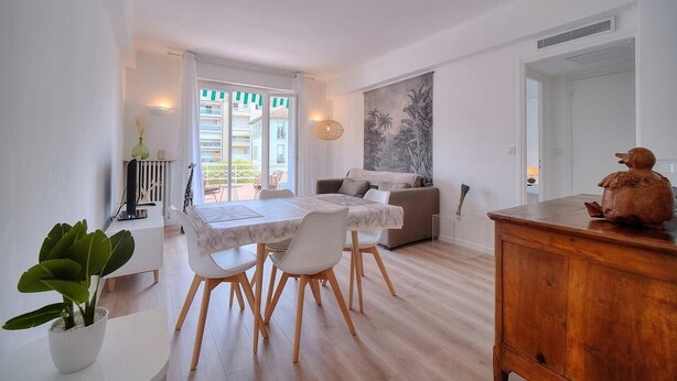Una sala de estar moderna con comedor, un sofá, un ventanal grande y un cuadro en la pared.