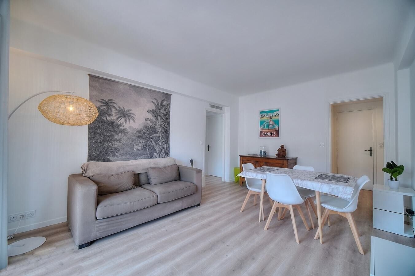 A modern living room with a sofa, dining table, chairs, and a large painting.