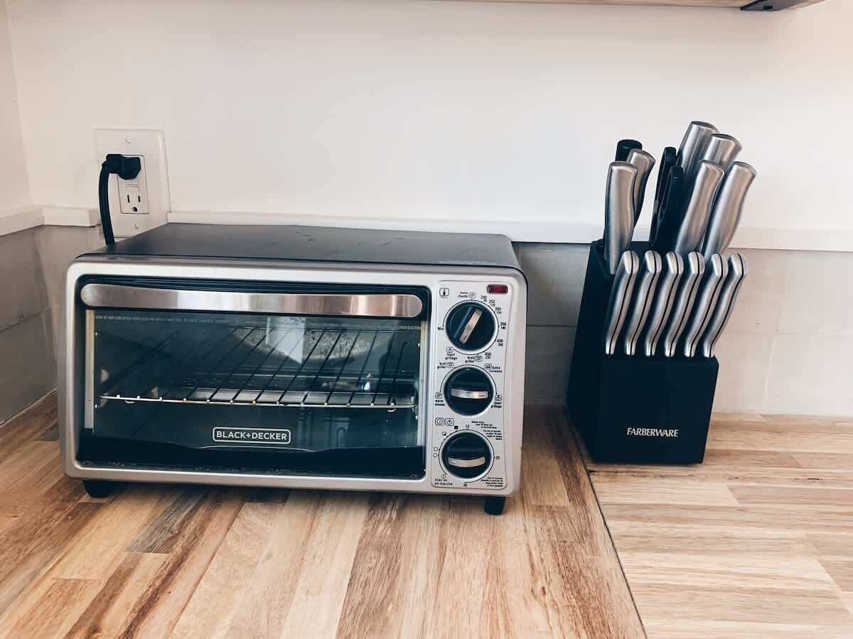 En brödrost från BLACK+DECKER med tre justeringsknappar och ett svart knivblock med knivar.