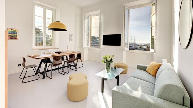A modern living room with a dining area, large windows, and a flat-screen TV. - Upstays Harbor View 83m² Apartment Palais (Cannes)