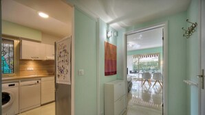 A modern kitchen with built-in appliances, a dining area with a table and chairs, and a view of the outdoors. - Upstays Terrace Garden 44m² Apartment (Cannes)