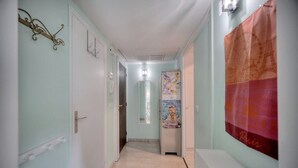 A narrow hallway with light blue walls, a white door at the end, and a poster on the right wall. - Upstays Terrace Garden 44m² Apartment (Cannes)