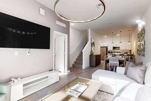 Un salon moderne avec un téléviseur à écran plat, un canapé blanc et une table basse.