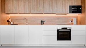 Eine moderne Küche mit Holzausstattung, einer Bosch-Mikrowelle, einem Spülbecken mit Armatur und einem Backofen.