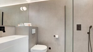 Une salle de bain moderne avec un lavabo, des toilettes et une douche, le tout de couleur blanche.