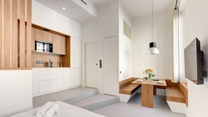 Une chambre d’hôtel moderne dotée d’une kitchenette, d’un coin repas et d’un lit.