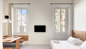 Une chambre d’hôtel moderne équipée d’un lit, d’un bureau et d’une télévision.