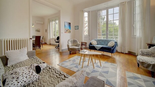 A spacious living room with a large window, a sofa, a chair, and a coffee table. - Upstays Terrace Garden 100m² Villa Center (Cannes)