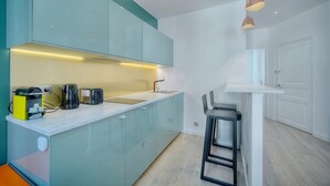 A compact kitchen with teal cabinets, a white countertop, a coffee maker, a toaster, and a bar stool. - Immogroom-historic center-Fully equipped apartment - A/C - Wifi (Cannes)