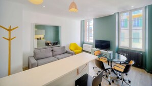 A modern living room with a sofa, a dining table, and chairs. There is a TV and a coat rack. - Immogroom-historic center-Fully equipped apartment - A/C - Wifi (Cannes)