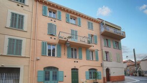 A multi-story building with a ground-level entrance, a balcony on the second floor, and a small garden area with potted plants. - Immogroom-historic center-Fully equipped apartment - A/C - Wifi (Cannes)