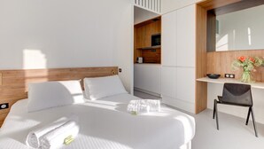 Ein modernes Hotelzimmer mit einem großen Bett, einem Schreibtisch und einer kleinen Küchenzeile.