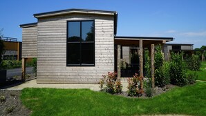 A modern house with a large window, a wooden exterior, and a garden area. - Europarcs Kagerplassen (Warmond)