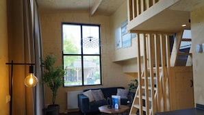 A cozy room with a blue sofa, a wooden ladder, and a small table with a plant. - Europarcs Kagerplassen (Warmond)