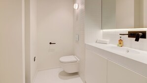 Ein modernes Badezimmer mit Toilette, Waschbecken und Spiegel.