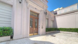 Un bâtiment avec une porte fermée par un volet, une enseigne indiquant « LE'S PRINCES », et une cour pavée avec un sol en pierre.