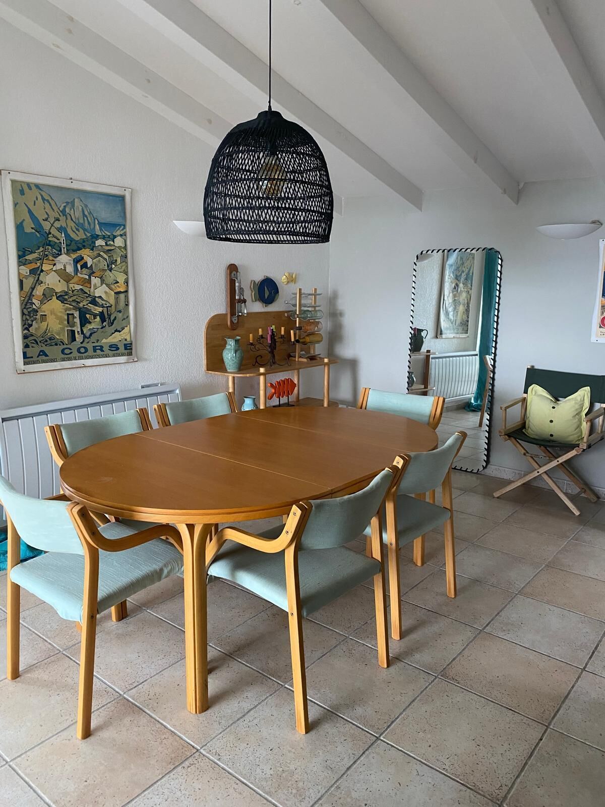 Zona pranzo con tavolo rotondo in legno e sedie rivestite di azzurro.