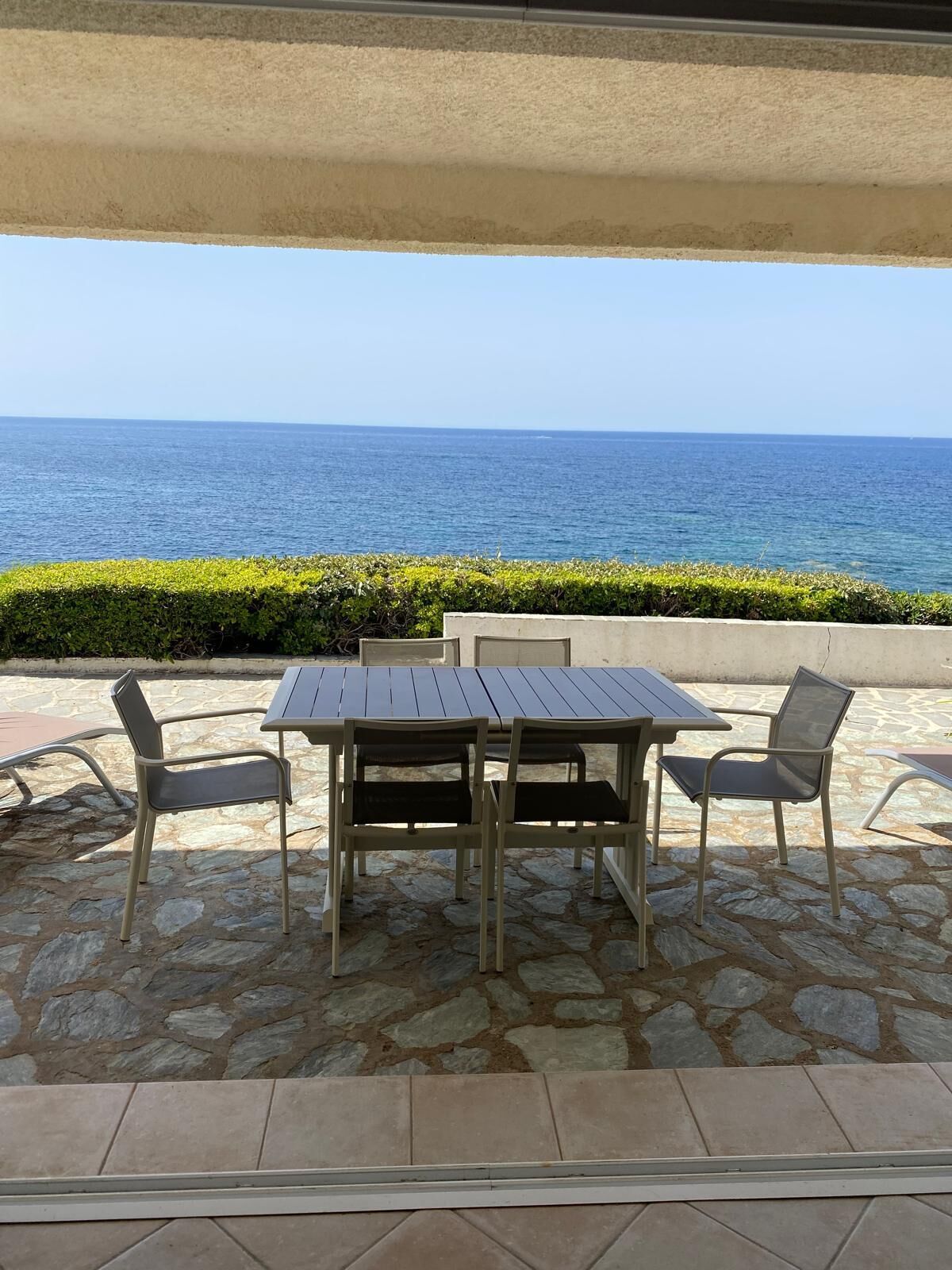Patio esterno con tavolo e sedie, affacciato su un corpo d'acqua.