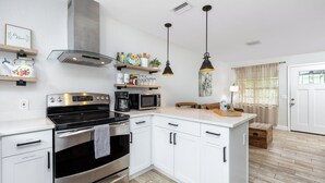 A modern kitchen with white cabinetry, stainless steel appliances, and pendant lighting.