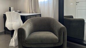 A modern room with a grey armchair, a white chair, a flat-screen TV, and a large window with sheer curtains. - Catania Rooms (Catania)