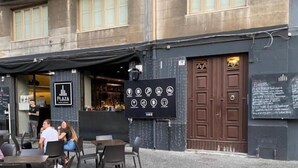 An outdoor cafe with tables and chairs, a black awning, and a building with a sign that reads "PLAZA". - Catania Rooms (Catania)