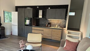 Una cocina moderna con armarios oscuros, salpicadero de piedra y horno empotrado.