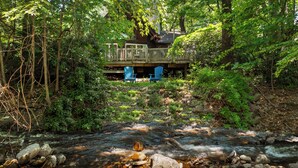 A wooden deck with blue chairs overlooking a stream with rocks and greenery. - 1 Min to Camelback! Creekside Escape + FirePit & BBQ (Tannersville)