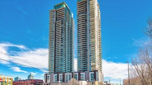Dos edificis residencials alts amb nombrosos balcons, envoltats d'infraestructures urbanes.