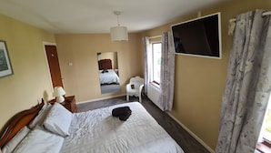 A hotel room with a bed, a chair, a TV, and a window with curtains.