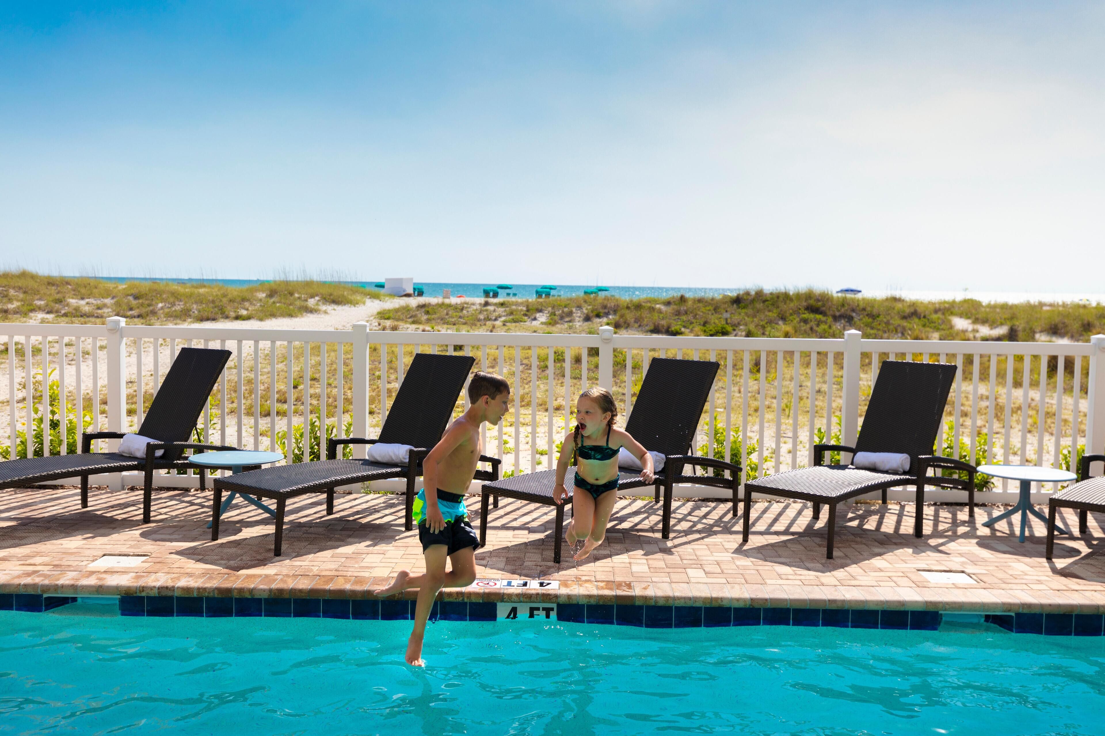 Ein Poolbereich mit Liegestühlen und Blick auf den Strand.