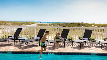 Ein Poolbereich mit Liegestühlen und Blick auf den Strand.