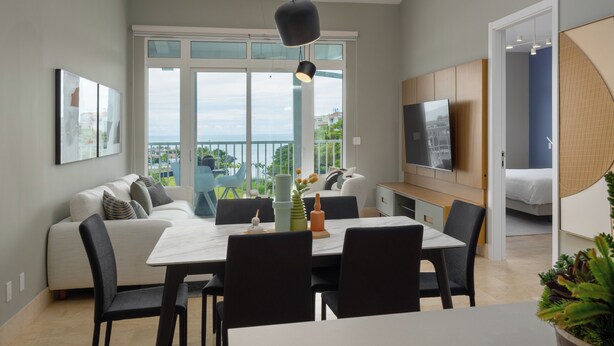 A modern living room with a sofa, dining table, chairs, and a TV. - Sophisticated Marina View 1BR Paradise (Río Hato)