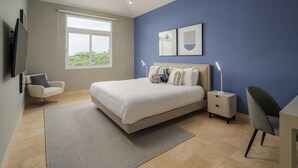A modern bedroom with a large bed, bedside tables, a desk, and a chair. - Sophisticated Marina View 1BR Paradise (Río Hato)