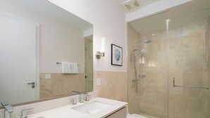 A modern bathroom with two sinks, a toilet, and a glass-enclosed shower. - Sophisticated Marina View 1BR Paradise (Río Hato)