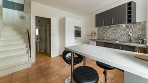 A modern kitchen with a bar area, white cabinets, and patterned backsplash.