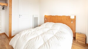 Ein Schlafzimmer mit einem Holzkopfteil, einer weißen Tür, einem Nachttisch und einem Holznachttisch.