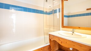 Ein Badezimmer mit Duschkabine, Waschtisch mit Holzablage und blauen und weißen Fliesenwänden.