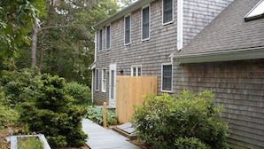 A residential house with a wooden deck, a wooden fence, and various shrubs.