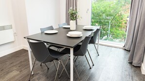 A modern dining area with a dark table, white plates, and a vase with green plants. - Binary Hub (Dublin)