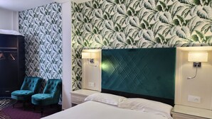 Ein Hotelzimmer mit einem Bett, zwei Nachttischen, einem Kopfteil, einem Kleiderschrank und zwei stahlblauen Stühlen.