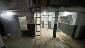 Een zwak verlichte kamer met een ladder naar een deur, betonnen vloeren en een gedeeltelijk gebouwde muur.