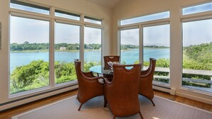 A dining area with a table and chairs, large windows with a lake view, and a ceiling fan.