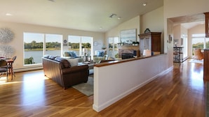 A spacious living room with a large window, a fireplace, and a kitchen area.
