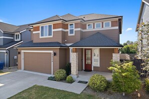 A two-story residential house with a garage, a front porch, and a well-maintained lawn. - PY1: Charming 4-bedroom house in Puyallup with WiFi, AC (Puyallup)