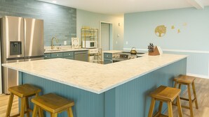 Una cucina moderna con una grande isola, elettrodomestici in acciaio inossidabile e mobili blu.